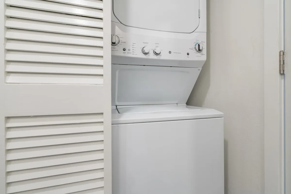 A practical laundry space with a stacked washer and dryer set neatly behind louvered doors. The area is clean, efficient, and easily accessible—integrated seamlessly into the home’s layout for added convenience.