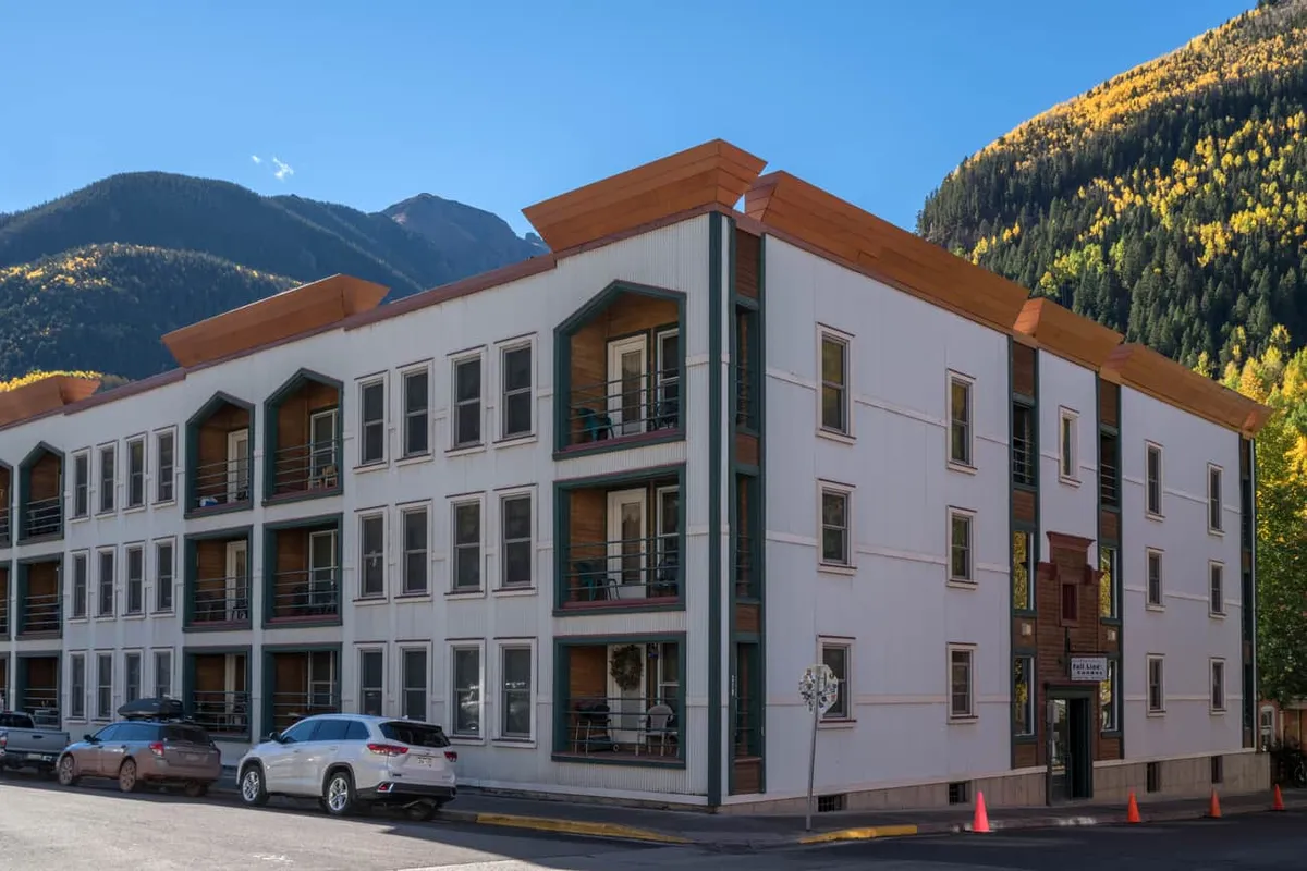 A scenic view of Telluride’s distinctive mountain architecture, with balconies facing dramatic mountain backdrops. The image shows people socializing outdoors, hinting at the proximity to nature and opportunities for exploration.